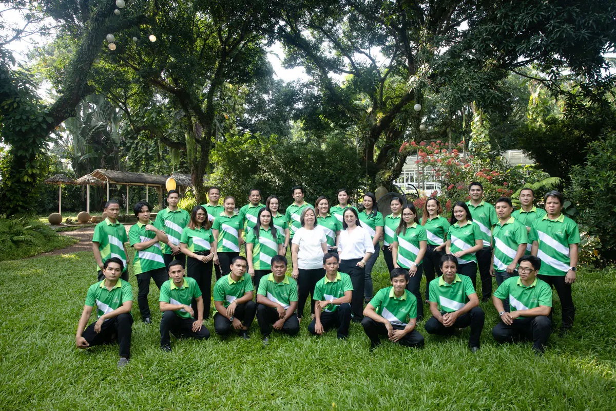 The Jardin de Miramar team on the lawn, most in green uniform polos, under the mature trees of the gardens