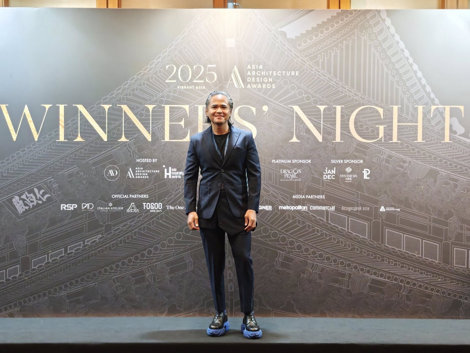 Formal event with architectural awards backdrop.